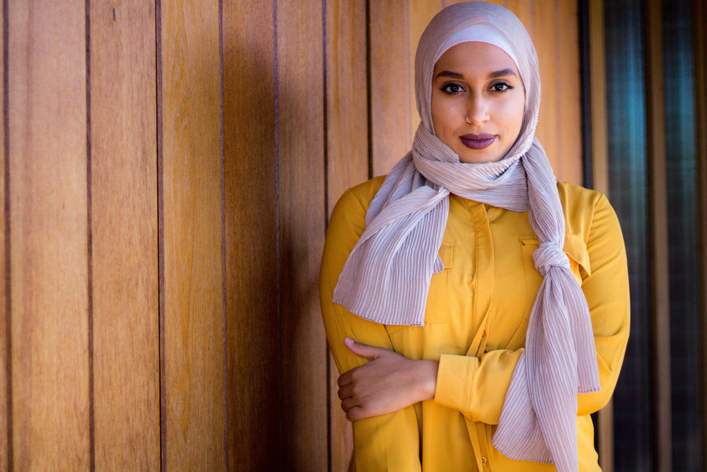 black muslim woman wearing a tan pleated hijab and modest gold long sleeve button up