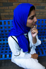 muslim woman wearing all white and a royal blue jersey hijab