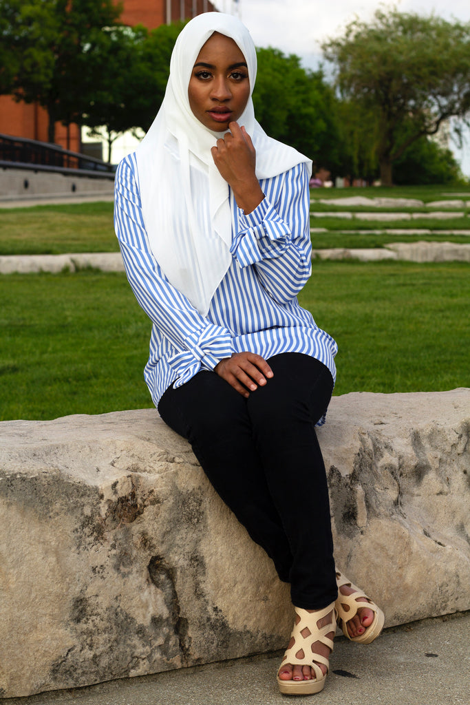 black muslim woman wearing white chiffon square hijab and long sleeve blouse with bow sleeves and blue and white stripes