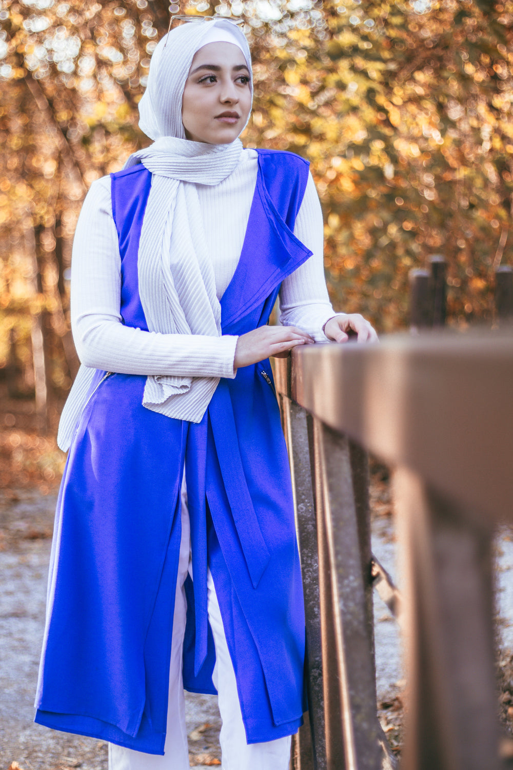 muslim woman wearing a royal blue sleeveless cascade jacket with zipper pockets and a white shimmer jersey hijab