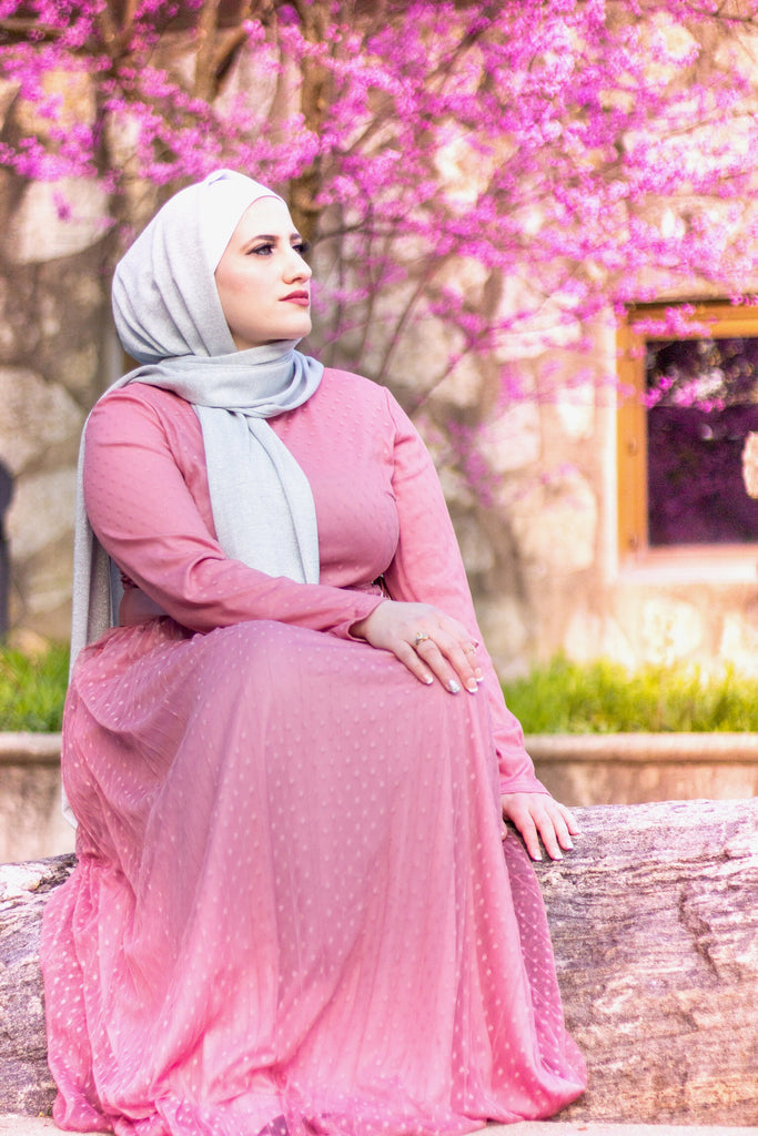 muslim woman wearing silver shimmer jersey hijab and a pink long sleeve maxi dress with polka dots and satin waist belt