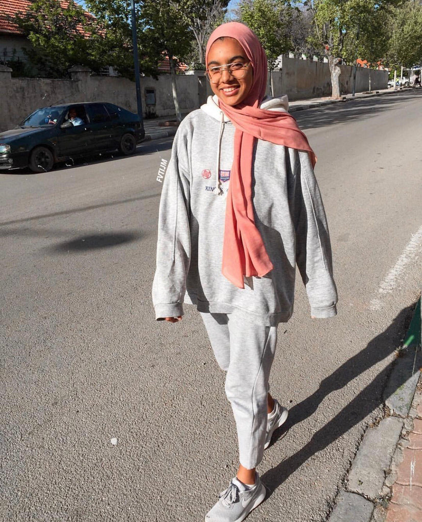 muslim woman walking down the street wearing all gray and a mauve bamboo hijab