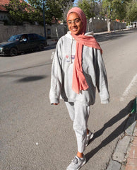 muslim woman walking down the street wearing all gray and a mauve bamboo hijab