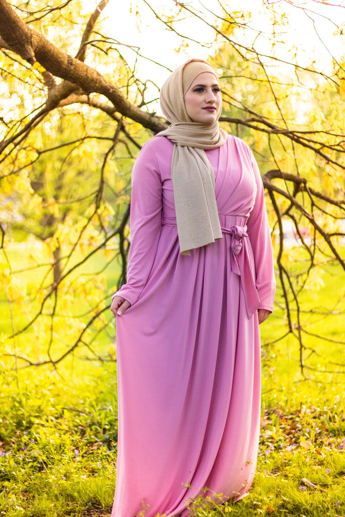 muslim woman wearing a gold shimmer jersey hijab and pink criss cross maxi long sleeve dress with pockets and a waist tie